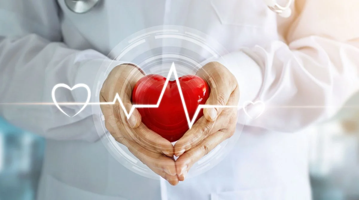 Doctor with stethoscope and red heart shape with icon heartbeat in hands on hospital background