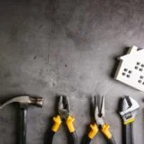 Wooden house and construction tools on stone pattern background with copy space.Home Repair concept, Repair maintenance concept, Renovation concept.