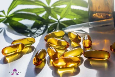 Medical cannabis products: leaf, capsules and CBD oil on white b