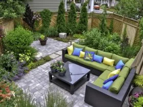 A beautiful small, urban backyard garden featuring a tumbled paver patio, flagstone stepping stones, and a variety of trees, shrubs and perennials add colour and year round interest.