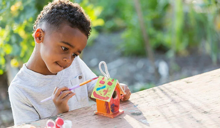 Little boy painting bird house